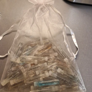 Samling av parfymprover från oriflame i organzapåse - En stor samling av parfymprover i en elegant organzapåse. Proverna kommer i små glasflaskor med vita lock, perfekt för att testa olika dofter. Påsen är genomskinlig och knyts med ett band. 1ml alla ca hälften kvar, blandat för dam och herr.