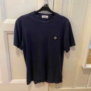Mörkblå t-shirt från Stone Island - Snygg mörkblå t-shirt från Stone Island med korta ärmar och en broderad logotyp på bröstet. Perfekt för en stilren och avslappnad look.