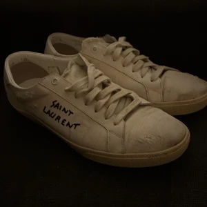 Vita sneakers från Saint Laurent - Snygga vita sneakers från Saint Laurent med handskriven logga på sidan. Skorna har klassisk snörning och en stilren design som passar perfekt för en avslappnad look. Skorna kostar drygt 7200kr men mitt priss ligger på 2899, skriv i dm ifall du har frågor eller funderingar|inget OG medföljer|
