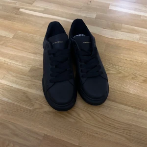  Alexander McQueen - Snygga svarta sneakers från Alexander McQueen med diskret logga på hälen. Skorna har en klassisk design med snörning och är tillverkade i skinn.