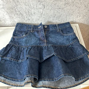 Jeanskjol med volanger - Jättegullig jeanskjol med volanger, midjemått ca. 36 cm. Köpte second hand och tyvärr inte kommit till användning då den känts lite längre än vad jag önskat (är ca. 150 cm lång)💕 Annars superfint skick.