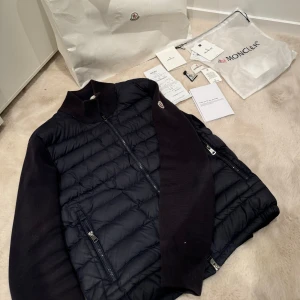 Moncler cardigan -  Marinblå 🟦Moncler cardigan i bra skick, däremot finns det ett litet hål vid armen som absolut inte syns vid användning, qr koden fungerar och nfc Scan ska funka , skriv om ni har några funderingar , Pris är inte hugget i Sten . 