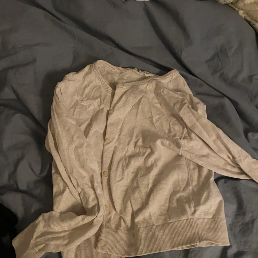 Säljer en stilren cremevit kofta från H&M. Den har långa ärmar och knappar framtill. Perfekt för lager-på-lager under kyligare dagar.. Neuletakit & Villapaidat.
