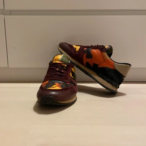 Valentino Rockrunner  - Snygga Valentino Rockrunner sneakers med ett unikt kamouflagemönster i orange, gul och svart. Skorna har en kombination av skinn och mocka med snörning och en bekväm sula. Pris kan diskuteras. Skriv i dm för fler frågor eller bilder!😊