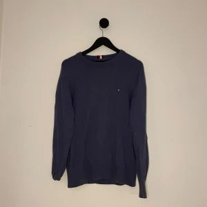 Blå tröja från Tommy Hilfiger - Snygg blå tröja från Tommy Hilfiger i en mjuk blandning av pima bomull och kashmir. Tröjan har en liten broderad logotyp på bröstet och rund halsringning. Perfekt för en stilren look. Hör gärna av er vid flera frågor eller funderingar! 