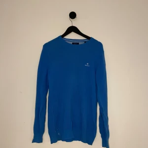Gant Tröja - Snygg blå tröja från GANT med rund halsringning och diskret logga på bröstet. Perfekt för en stilren look. Tröjan har långa ärmar och är tillverkad i ett bekvämt material. Hör gärna av er vid flera frågor eller funderingar! 