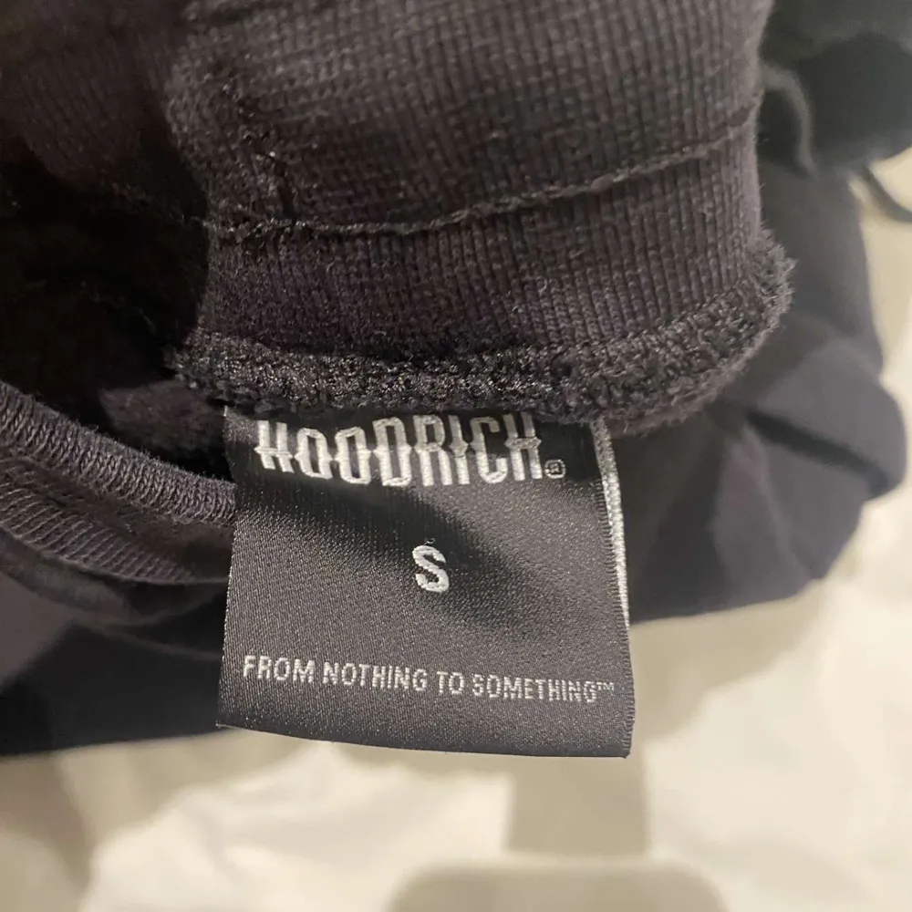 Säljer ett par svarta mjukisbyxor från Hoodrich med en blå och vit logga på sidan. . Farkut & Housut.
