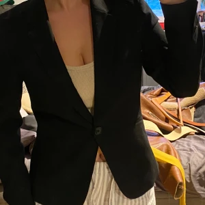 Svart kavaj från H&M - Snygg svart kavaj från H&M i storlek 36. Kavajen har en klassisk design med en knapp framtill och långa ärmar. Perfekt för en stilren look.