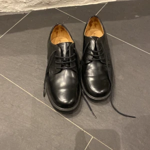 Svarta skinnskor från Polo Ralph Lauren - Snygga svarta skinnskor från Polo Ralph Lauren med klassisk snörning. Perfekta för en stilren look. Skorna har en robust sula med greppvänliga mönster.