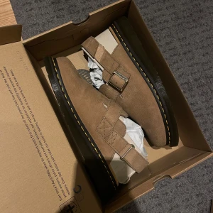 Bruna mockaskor från Dr. Martens - Säljer min killes helt nya dr martens jorge 11 i färgen ”savannah tan” sandfärgade/bruna.  Säljes pga går inte att retunera, beställde för länge sedan och skulle bli en julklapp men stlken var för stor. Han har 42,5 vanligtvis. Dessa i storlek 43.  Artikeln skickas i sin orginalkartong. Org pris 1700