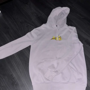 Lila hoodie med tryck - Säljer en lila hoodie med ett gult tryck på bröstet. Hoodien har en klassisk design med lång ärm och en bekväm huva. Perfekt för en avslappnad stil.