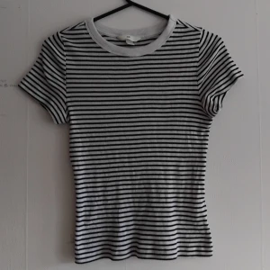 Randig t-shirt från H&M - En randig t-shirt i svart och vitt. Korta ärmar och kort midja. Använt ett fåtal gånger, inga defekter