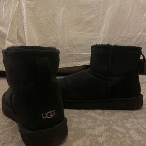 Svarta UGGs - Säljer ett par klassiska svarta UGG boots med mjukt foder. Perfekta för kalla dagar med sin varma och bekväma design. De har en rund tå och en robust sula för bra grepp. Använda hyfsat många gånger men är i bra skick.