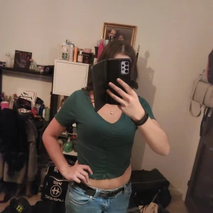 Grön croppad t-shirt - Snygg grön croppad t-shirt med korta ärmar och v-ringad hals. Perfekt för en avslappnad stil.