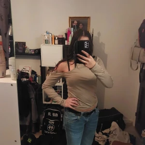 Beige offshoulder topp - Säljer en stilren beige offshoulder topp med långa ärmar. Perfekt för en avslappnad men trendig look. Passar bra till jeans eller kjol.