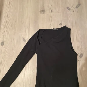 Svart oneshoulder body - Snygg svart oneshoulder bodysuit med lång ärm. Tillverkad i ett mjukt och stretchigt material för bästa passform.