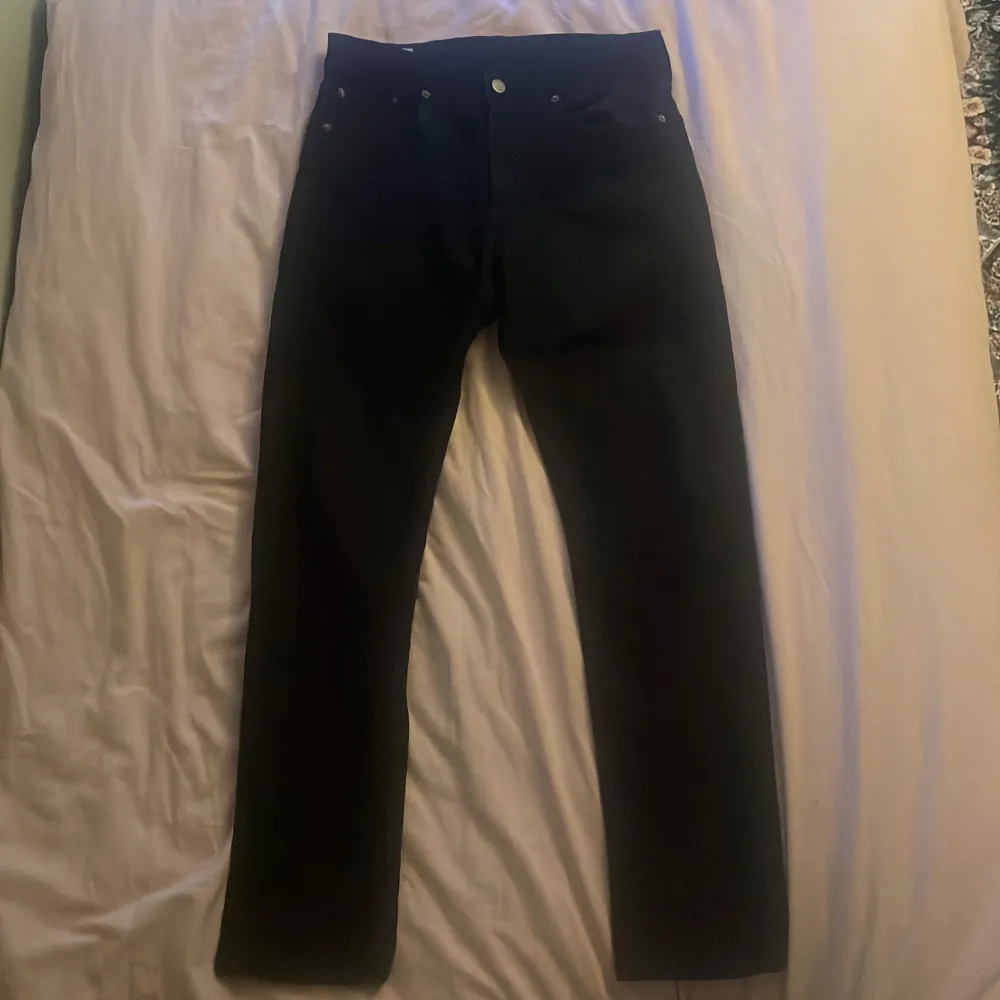 Säljer ett par svarta jeans i storlek W30 L32. De är i bra skick och har en klassisk design med fem fickor och knappgylf. Perfekta för både vardag och fest!. Farkut & Housut.