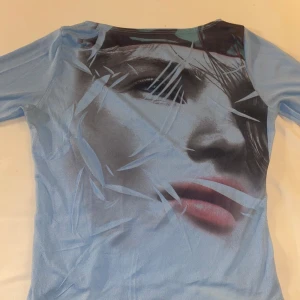 As snygg blå y2k tröja med tryck🤩 - Super snygg y2k tröja med tryck av en tjej i fram🤩🤩 Finns ingen lapp men passar S/M💓 Genomskinlig som typ en intimissmi tröja och ungefär till midjan i längden Skriv för fler bilder💗  