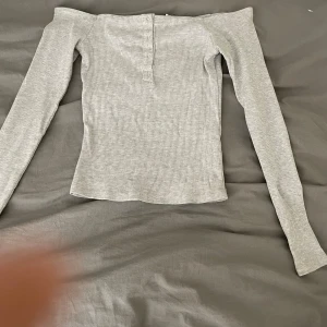 Of shoulder tröja  - Den här sitter riktigt snyggt på kroppen. Och ser ut som ny. Knapparna går att knäppa upp om man skulle vilja det.