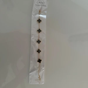 Guldarmband med svarta fyrklöver - Säljer ett elegant guldarmband med svarta fyrklöver. Armbandet är tillverkat i rostfritt stål och har en justerbar kedja för perfekt passform. Perfekt för att lägga till en touch av lyx till din outfit! Platerad i guld och kan användas 24/7, även i vatten! har ett exakt likadant till som jag använder