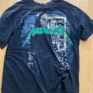 Svart Metallica t-shirt - Säljer en svart Metallica t-shirt med ett coolt tryck på baksidan. T-shirten är i storlek S men är väldigt Baggy och har korta ärmar. Perfekt för alla Metallica-fans! Den är i välanvänt skick men fortfarande riktigt snygg. Passar bra till vardags eller på konsert.💞