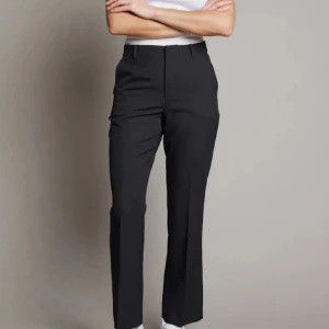 Svarta kostymbyxor från BikBok - Säljer ett par snygga svarta kostymbyxor från BikBok i storlek petite 34. Byxorna är högmidjade och har en rak passform. Perfekta för både jobb och fest! De är i nyskick och har praktiska fickor baktill. Materialet känns bekvämt och ser stilrent ut. Passa på att fynda dessa klassiska byxor!