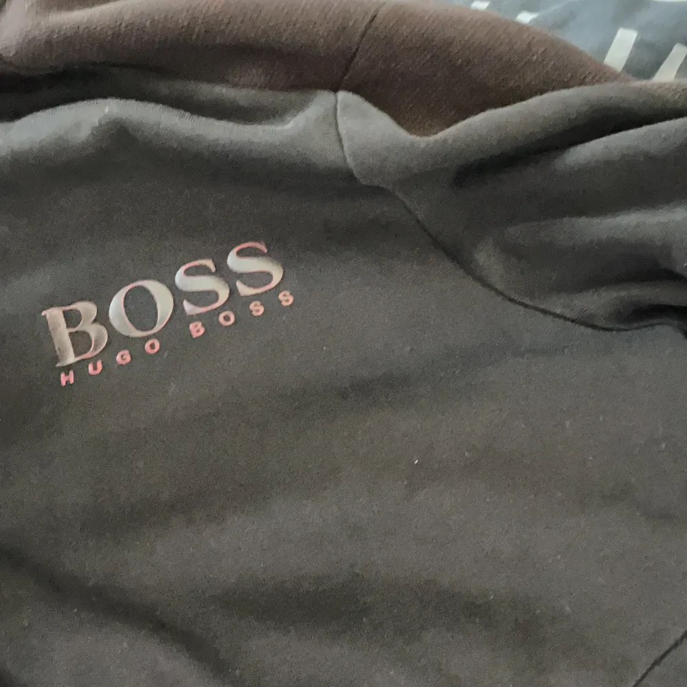 Säljer en snygg svart jacka från Hugo Boss i storlek M. Jackan har en dragkedja i rött som går hela vägen upp till kragen och två fickor på framsidan. Den har en broderad Hugo Boss-logga på bröstet. Perfekt för höst och vår!. Jackor.