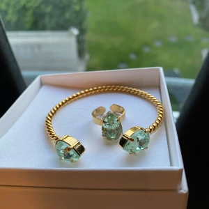 Guldarmband och ring med gröna stenar - Säljer ett snyggt set med ett guldarmband och en matchande ring från Caroline Svedbom. Använt några gånger.  Nypris ring: 595kr Nypris armband: 795kr  Säljer båda för 800kr 💕💕