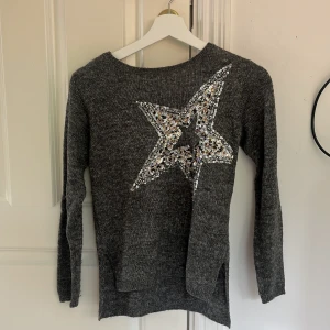 Grå och stickad tröja - Snygg stickad tröja i storlek 146/152 från hm. Den har paljetter i en stjärna och snygg till t.ex. bootcut jeans