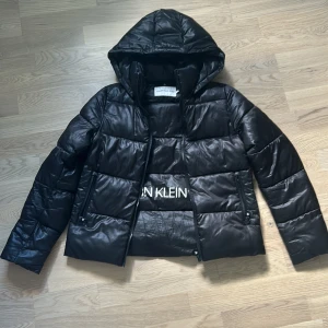 Svart pufferjacka från Calvin Klein Jeans - Säljer en snygg svart pufferjacka från Calvin Klein Jeans. Jackan är i bra skick och har en normal passform. Den är långärmad och har en dragkedja framtill. Perfekt för höst och vinter!