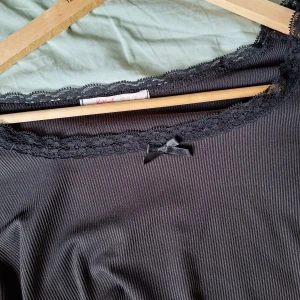Svart ribbad topp med spetsdetaljer - Säljer en snygg svart ribbad topp från Romwe. Toppen har långa ärmar och en fin spetskant runt halsringningen, samt en liten rosett framtill,jättegullig till hösten!. Hör av dig vid frågor eller för fler bilder, använd gärna köp nu 💗