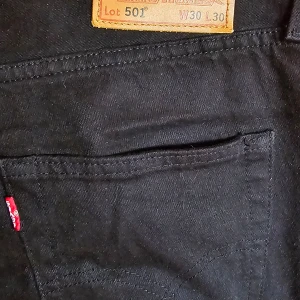 Levis 501 - Jeans svarta med knappar fram. Levis 501- modellen 100 procent bomull  Storlek W30 L30   Mått: Midja 40 cm Innerbenslängd: 74 cm Lårvidd: 27 cm Fotvidd: 18 cm Byxlinningen (4 knappar): 18 cm    Fint skick!    Köparen står för fraktkostnad. F