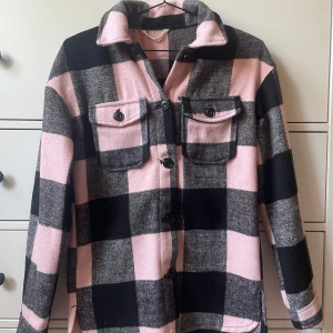 Rutig jacka från H&M - Säljer en superfin rutig jacka från H&M i storlek 158, men passar mig som har xs. Jackan är i rosa och svart med stora rutor och har långa ärmar. Den har två bröstfickor med knappar och knäppning fram. Perfekt för höst och vår!
