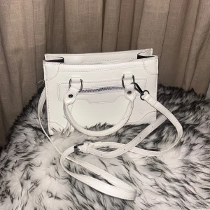 Vit handväska med dragkedja - Säljer en snygg vit handväska som har en dragkedja på framsidan och en justerbar axelrem. Perfekt för både vardag och fest! 👜✨