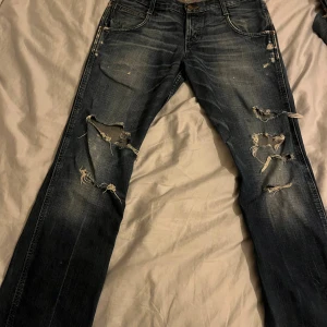 Jeans - Sjukt coola jeans med snygga hål på benen. Dem är bootcut med en låg midja. Lite slitningar längst ner på benen men annars i väldigt bra skick! Hör av dig vid frågor💕💕