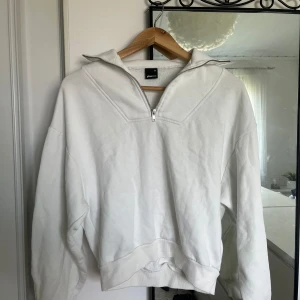 Vit hoodie från Gina Tricot - Säljer en superfin vit hoodie utan luva från Gina Tricot i storlek XS passar S med💕. Den har en halv dragkedja framtill och en mysig, lös passform. Perfekt för höst och vinter. Hoodien är i nyskick och gjord av mjukt bomullsmaterial. Passar både till vardags och chillkvällar hemma. 🥰