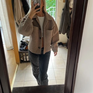 Beige jacka från NA-KD - Säljer en snygg beige jacka från NA-KD. Den har en oversized passform med stora fickor framtill och knappar. Perfekt för höst och vår! 