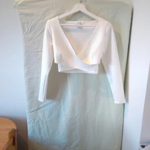 Vit omlottopp - Säljer en superfin vit omlottopp i storlek S. Den har en v-ringad design och långa ärmar, perfekt för både vardag och fest. Toppen är croppad vilket ger en modern och trendig look. Passar perfekt till höst- och våroutfits!