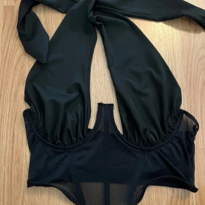 Svart baddräkt med öppen rygg - Säljer en stilren svart halterneck topp med öppen rygg. Materialet är mjukt och bekvämt