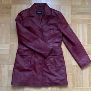 Vinröd skinnjacka från Auluna - Snygg vinröd skinnjacka från Auluna med knappar och två rymliga fickor!