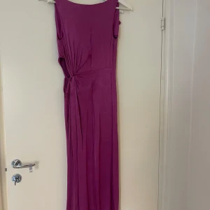 Lila satinklänning med öppning vid midjan - Lila satinklänning med öppning vid midjan och slits. 