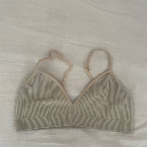 Beige ribbad topp - Säljer en superfin beige/gul ribbad topp med justerbara axelband. Toppen är i ett mjukt och stretchigt material som ger en bekväm passform.