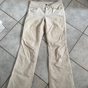 Beige manchesterbyxor från H&M Divided - Säljer ett par snygga beige manchesterbyxor från H&M Divided. De är i storlek EUR 38 och har en klassisk straight passform. Byxorna har en lågmidjad design, bootcut, med knappar och dragkedja framtill. Perfekta för höst och vinter med sitt mjuka och varma material. De har också praktiska fickor både fram och bak. skriv vid frågor💗