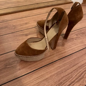 Bruna mockapumps från Zara  - Snygga bruna mockapumps från Zara Basic med hög klack och platåsula i flätad stil. De har en elegant rem över foten som ger extra stöd. Perfekta för en utekväll eller fest! 🥿✨