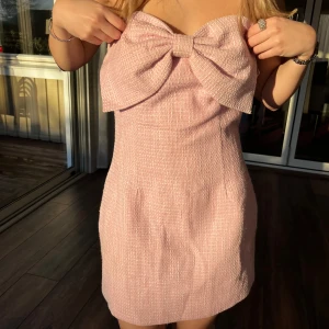 Rosa axelbandslös klänning med stor rosett - Säljer en superfin rosa axelbandslös klänning med en stor rosett framtill. Klänningen är kort (är 157 för referens)!💕💕 hade på midsommar, inte använd sen dess!