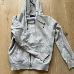 Grå hoodie från Ralph Lauren - Säljer en snygg och bekväm grå hoodie från Ralph Lauren. Den är 8/10 i skick. Om ni har några frågor om hoodien är det bara att skriva och priset är ej hugget i Sten 