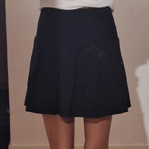 Svart kortkjol - Säljer en svart kortkjol i mycket bra skick. Säljer då jag har två. (Det är ingen fläck på kjolen utan det är spegel) Den är I storlek 32