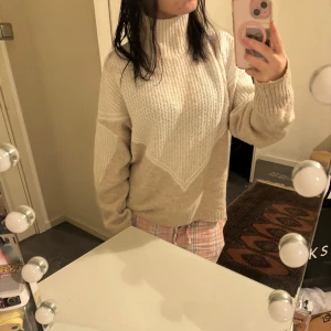 Beige stickad polotröja - Mysig beige stickad polotröja i oversized passform. Perfekt för kalla dagar med sin varma och bekväma design. Tröjan har långa ärmar och ribbade detaljer vid ärmslut och nederkant. En stilren och enkel tröja som passar till allt!