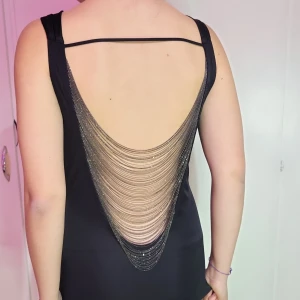 Toppar - Svart linne med "strassliknande" detaljer baktill. Öppen i ryggen där kedjorna faller hela vägen ner. Endast använd en gång så den är i toppskick. Märke: GUESS by Marciano Nypris: 2000kr 