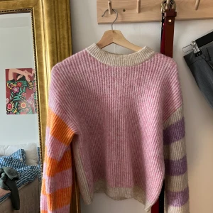 Envii stickad tröja ullmix  - Fin och mysig stickad tröja från Envii med randigt mönster i rosa, lila, orange och beige/vit. Modellen heter Envii Enhero LS knit. Storlek XXS men passar XS-S också. Kan skickas mot fraktkostnad eller hämtas i centrala Stockholm. Material 44% återvunnen polyester, 40% polyamid, 12% Ull, 2% akryl, 2% viskos